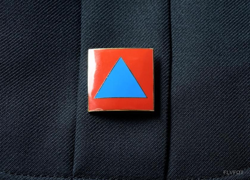 Det internationale Civilforsvarsmærke 4.3.2. Beredskabsforbundets logo Emaljemærke med blå trekant på orange bund.